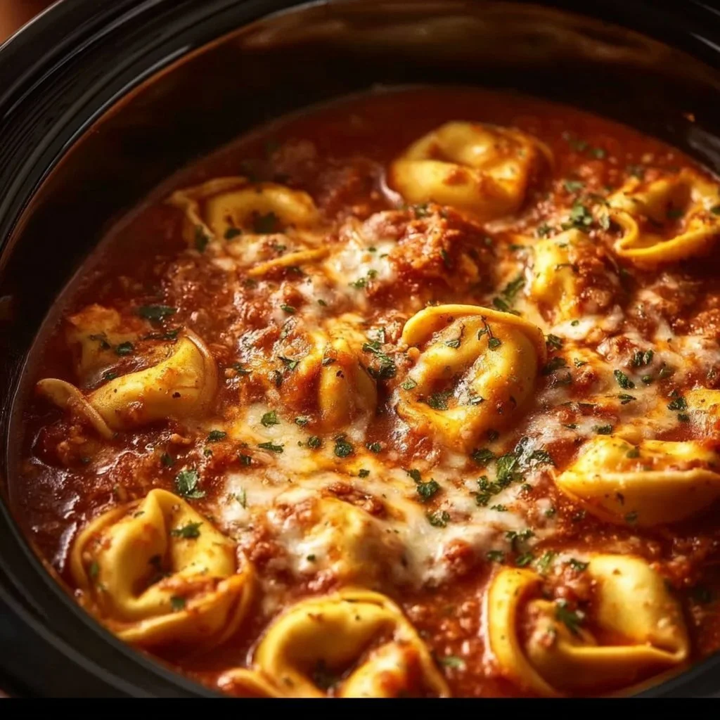 A bowl of slow cooker cheesy tortellini garnished with herbs.